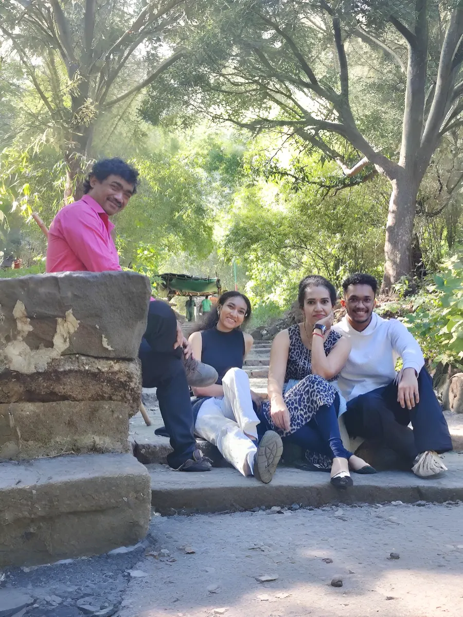The four of the family together outdoors under trees